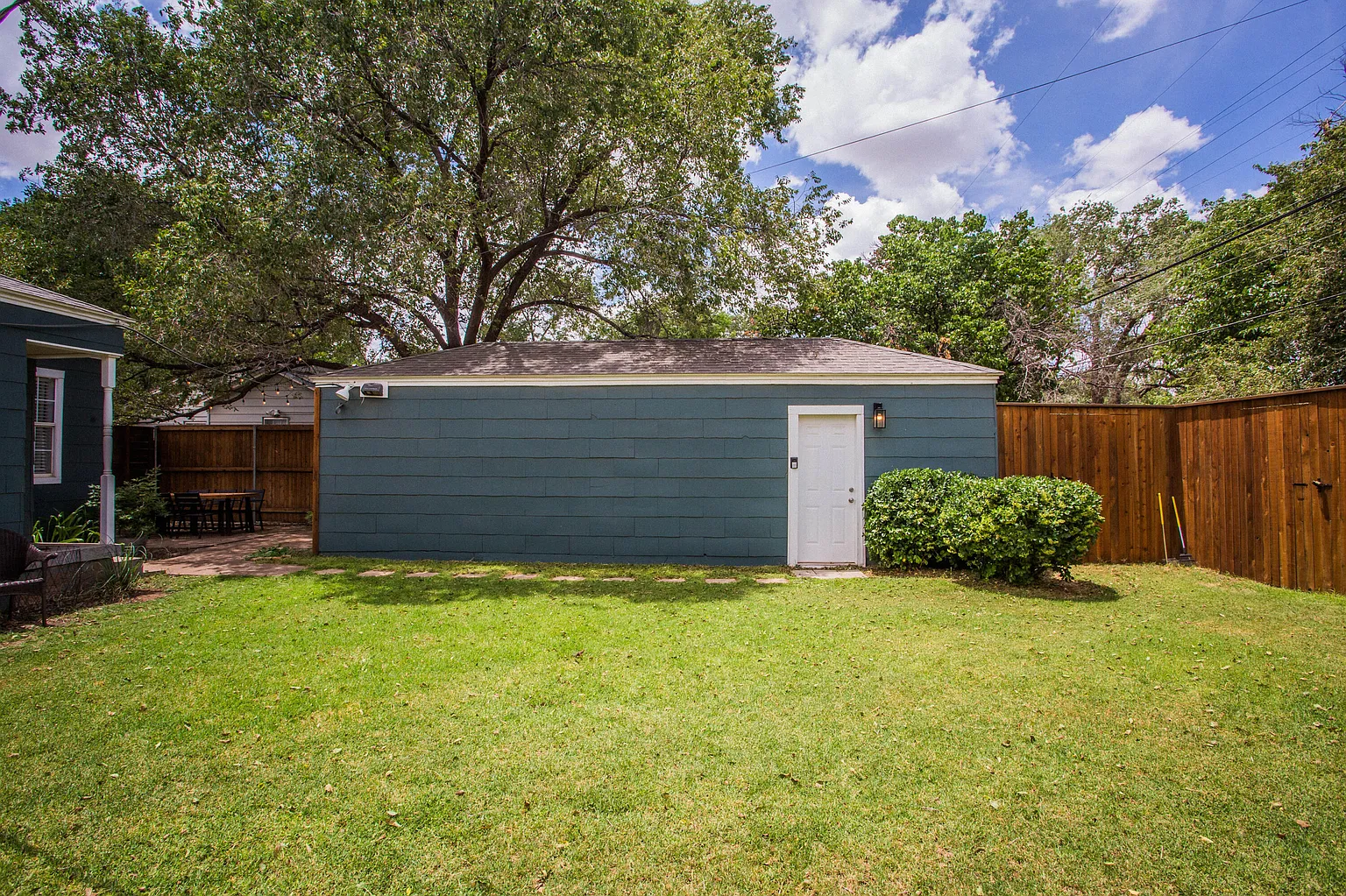 Teal garage apartment behind the main house with a grassy backyard